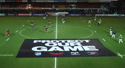 261213 - Newport Gwent Dragons v Cardiff Blues, RaboDirect PRO12 - Dragons and Blues players warm up as protest banner is placed on the pitch before the start of the match