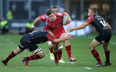 210815 - Newport Gwent Dragons v Scarlets, Pre-Season Friendly match - Scarlets Steffan Evans is tackled by Dragons Cory Hill and Tom Prydie