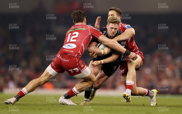 220423 - Dragons v Scarlets - United Rugby Championship - Judgement Day - Angus O'Brien of Dragons is tackled by Johnny Williams and Kieran Hardy of Scarlets 