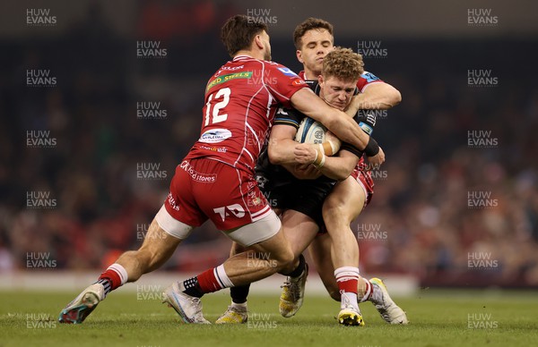 220423 - Dragons v Scarlets - United Rugby Championship - Judgement Day - Angus O'Brien of Dragons is tackled by Johnny Williams and Kieran Hardy of Scarlets 