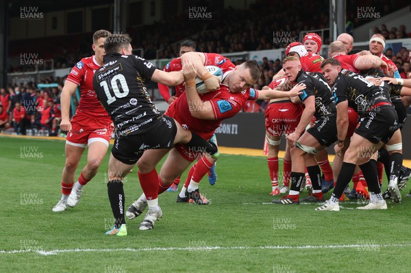 230422 - Dragons v Scarlets, United Rugby Championship - Rob Evans of Scarlets powers through the challenge from Sam Davies of Dragons to score try