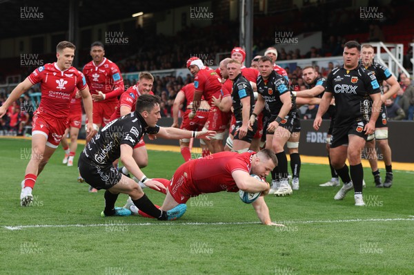 230422 - Dragons v Scarlets, United Rugby Championship - Rob Evans of Scarlets powers through the challenge from Sam Davies of Dragons to score try