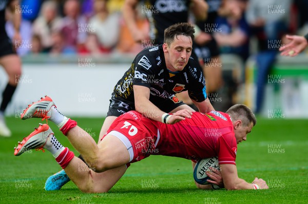 230422 - Dragons v Scarlets - United Rugby Championship - Steff Evans of Scarlets is tackled by Sam Davies of Dragons