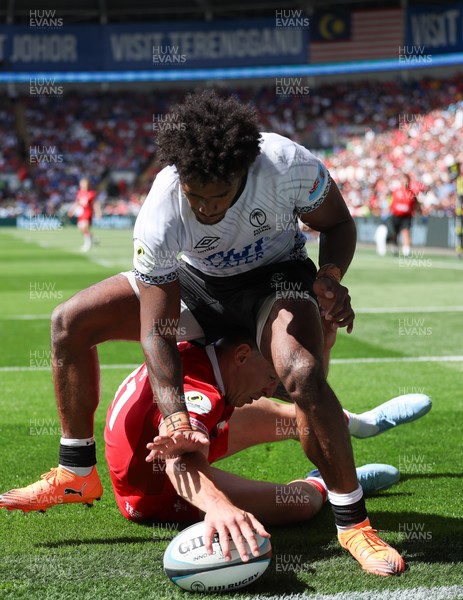 040726 - Fiji v Wales, Nations Championship - Josh Adams of Wales reaches between the legs of Selestino Ravutaumada of Fiji to score try