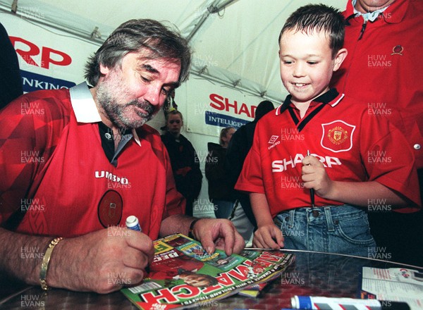 260797 - Footballer George Best signs autographs after having his footprints cast in concrete at Leekes store in Llantrisant