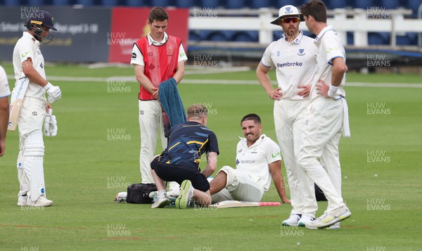 250623 - Glamorgan v Sussex, LV= Insurance County Championship, Div 2 - Kiran Carlson of Glamorgan receives treatment to his left ankle after taking a knock
