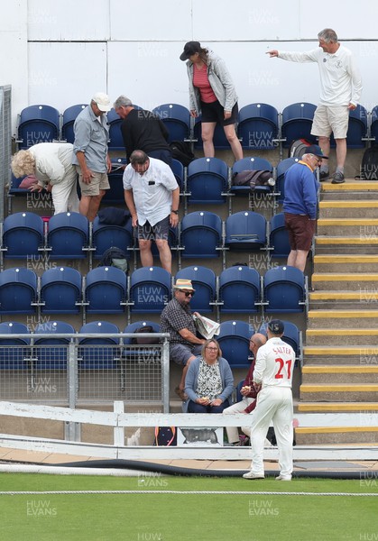 250623 - Glamorgan v Sussex, LV= Insurance County Championship, Div 2 - Spectators look for the ball as Andrew Salter of Glamorgan waits after it is hit into the stand for six runs