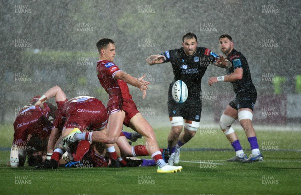 140423 - Glasgow Warriors v Scarlets - United Rugby Championship - Kieran Hardy of Scarlets puts in a clearance kick under pressure from Lewis Bean in atrocious weather conditions