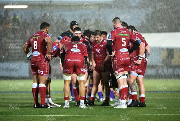 140423 - Glasgow Warriors v Scarlets - United Rugby Championship - Scarlets players huddle in atrocious weather during a break in play