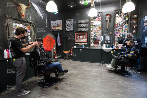 150321 - The first customers at Swyd Tattoo and Barber Shop in Cardiff city centre get haircuts as barbers and hairdressers on the first day they are allowed to reopen in Wales after the Welsh Government relaxed COVID19 lockdown restrictions in the country Restrictions relating to tattoos have yet to be lifted