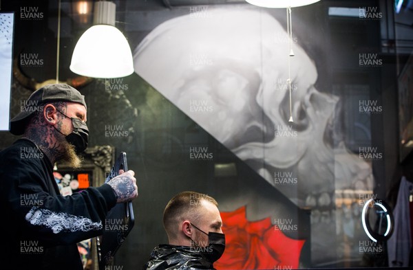 150321 - The first customers at Swyd Tattoo and Barber Shop in Cardiff city centre get haircuts as barbers and hairdressers on the first day they are allowed to reopen in Wales after the Welsh Government relaxed COVID19 lockdown restrictions in the country Restrictions relating to tattoos have yet to be lifted