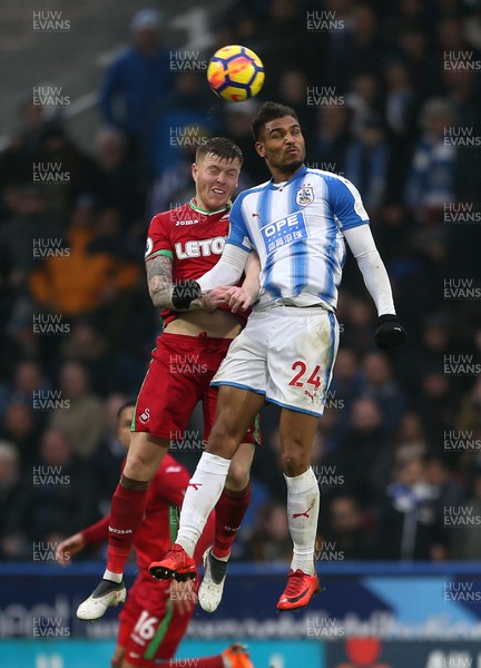 100318 - Huddersfield Town v Swansea City - Premier League - Alfie Mawson of Swansea and Steve Mounie of Huddersfield go up for the ball