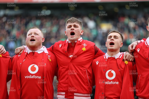 240224 - Ireland v Wales - Guinness 6 Nations Championship - Keiron Assiratti, Alex Mann and Cameron Winnett of Wales sing the anthem