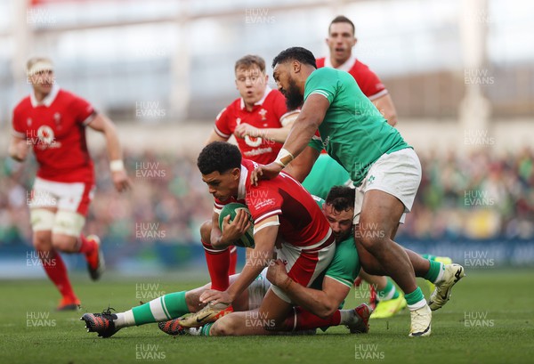 240224 - Ireland v Wales - Guinness 6 Nations Championship - Rio Dyer of Wales is tackled by Robbie Henshaw and Bundee Aki of Ireland 