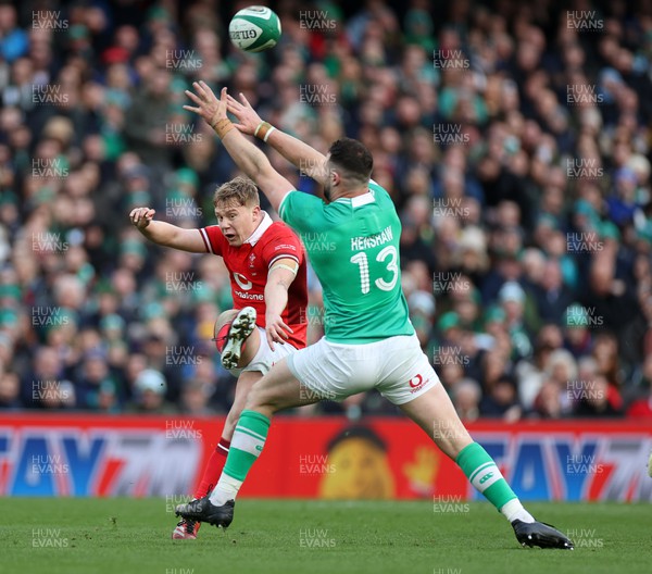 240224 - Ireland v Wales - Guinness 6 Nations Championship - Sam Costelow of Wales kicks the ball past Robbie Henshaw of Ireland 