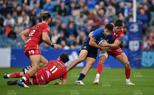 161021 - Leinster v Scarlets - United Rugby Championship - Hugo Keenan of Leinster is tackled by Ryan Conbeer, left, and Tomas Lezana of Scarlets