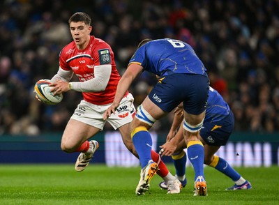 270326 - Leinster v Scarlets - United Rugby Championship - Joe Hawkins of Scarlets is tackled by Max Deegan and Jamison Gibson-Park of Leinster 