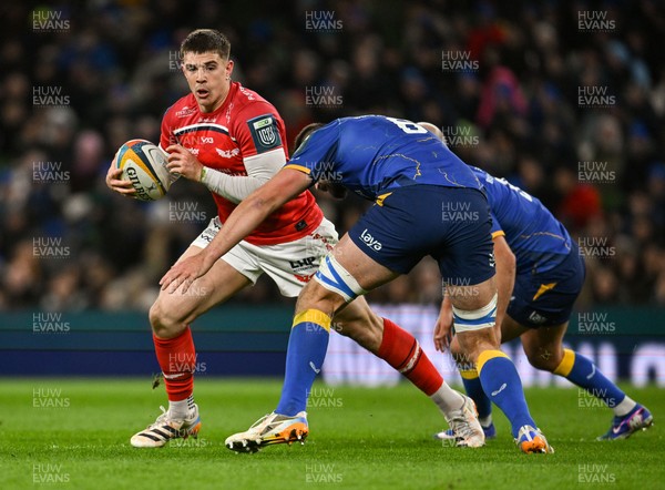 270326 - Leinster v Scarlets - United Rugby Championship - Joe Hawkins of Scarlets is tackled by Max Deegan and Jamison Gibson-Park of Leinster 
