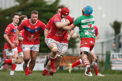 250323 - Llandovery v Llanelli - Indigo Group Premiership - Ben Williams of Llanelli hands off Stuart Worrall of Llandovery