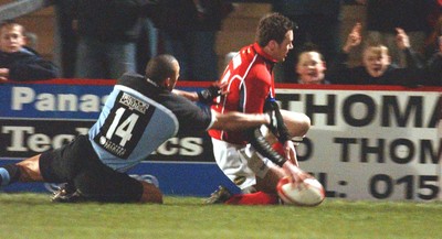 040203 - Llanelli v Cardiff - Welsh Premiership - Llanelli's Mark Jones crosses to score try despite tackle by Anthony Sullivan