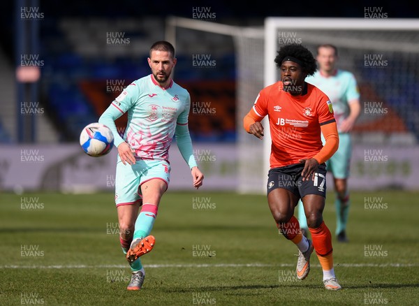 130321 - Luton Town v Swansea City - Sky Bet Championship - Conor Hourihane of Swansea City holds off the challenge from Pelly Ruddock Mpanzu of Luton Town