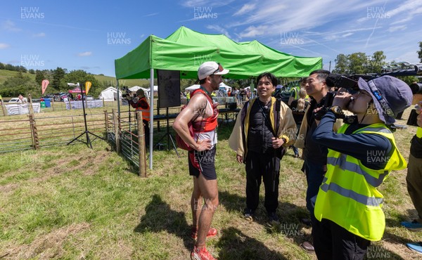 130626 - Man v Horse, Llanwrytd Wells - First runner across the finish line Daniel Connolly from Keswick is interviewed by a Japanese film crew at the end of  the annual Man v Horse Race held at Llanwrytd Well, Powys, Wales