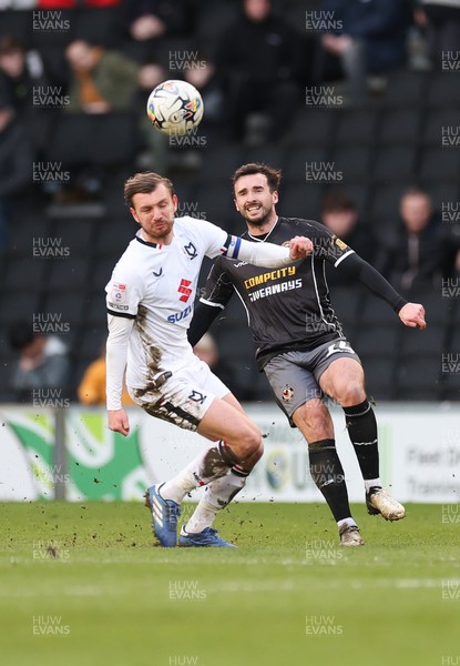 240224 - MK Dons v Newport County, EFL Sky Bet League 2 - Aaron Wildig of Newport County plays the ball as Alex Gilbey of MK Dons closes in