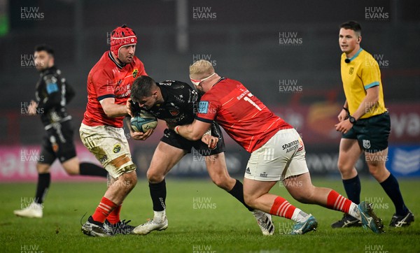 050322 - Munster v Dragons - United Rugby Championship - Lewis Jones of Dragons is tackled by John Hodnett, left, and Jeremy Loughman of Munster