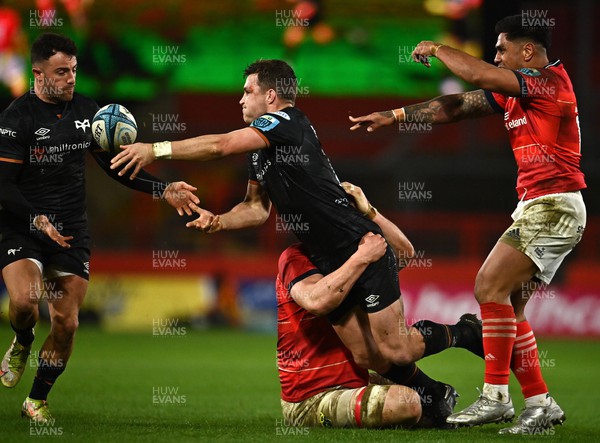 170223 - Munster v Ospreys - United Rugby Championship - Michael Collins of Ospreys offloads the ball to team-mate Luke Morgan as he is tackled by Gavin Coombes of Munster
