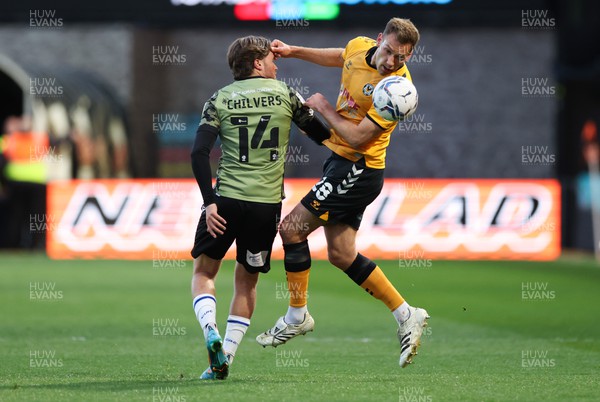 220422 - Newport County v Colchester United, Sky Bet League 2 - Mickey Demetriou of Newport County heads the ball forward as Noah Chilvers of Colchester United closes inl