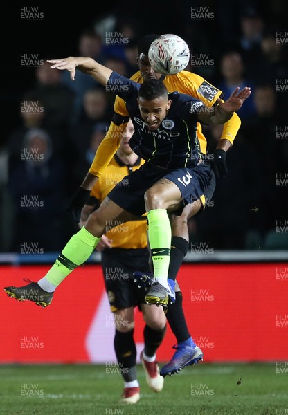 160219 - Newport County v Manchester City - FA Cup 5th Round - Danilo of Manchester City is challenged by Tyreeq Bakinson of Newport County in the air
