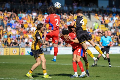 250426 - Newport County v Oldham Athletic - Sky Bet League 2 - Matthew Baker of Newport County challenges for the aerial ball with Reagan Ogle of Oldham Athletic
