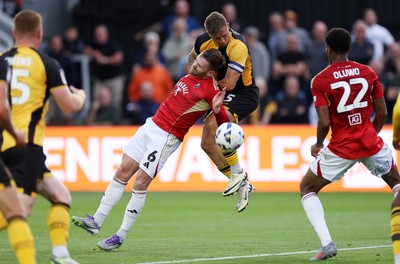 190825 - Newport County v Salford City - SkyBet League Two - Oliver Turton of Salford City and James Clarke of Newport County go up for the ball