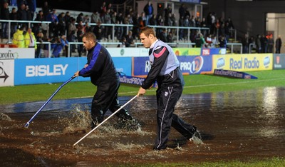 04.11.11 - Newport-Gwent Dragons v Cardiff Blues - RaboDirect PRO12 - Sam Hobbs helps clear the water logged pitch at Rodney Parade before the game is postponed. 