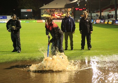 04.11.11 Dragons v Blues - RaboDirect PRO 12 - Ground staff attempt to clear rain water before kick off as referee Nigel Owens looks on 