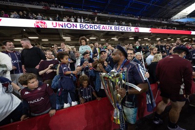 240525 - Northampton Saints v Union Bordeaux-Begles, EPCR Champions Cup Final - Union Bordeaux-Begles players celebrate with the trophy and fans