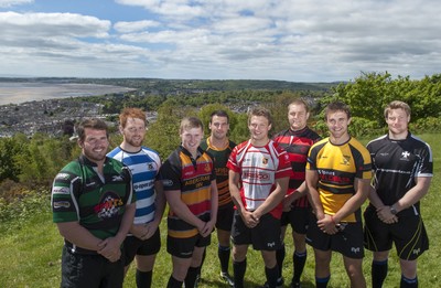 220513 - Ospreys - Pictured with Swansea Bay in the background are Opsreys players LtR: Ryan Bevington in Porthcawl kit, Dan Baker in Astradgynlais kit, Dafydd Howells in Abercrave kit, Scott Baldwin in Bridgend Athletic kit, Dan Biggar in Gorseinon kit, James King in Mold kit, Ashley Beck in Skewen kit and Jonathan Spratt in Neath Athletic kit