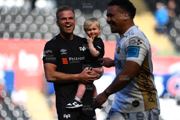 080522 - Ospreys v Dragons - United Rugby Championship - Gareth Anscombe of Ospreys with daughter Teifi and Aki Seiuli of Dragons at the end of the game