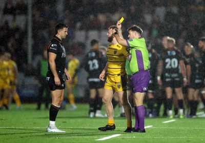 241026 - Ospreys v Dragons - United Rugby Championship - Referee Ben Whitehouse gives Aneurin Owen of Dragons a yellow card