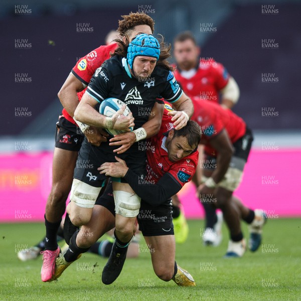 300324 - Ospreys v Emirates Lions - United Rugby Championship - Justin Tipuric of Ospreys is tackled by Jordan Hendrikse  and Erich Cronje of Lions