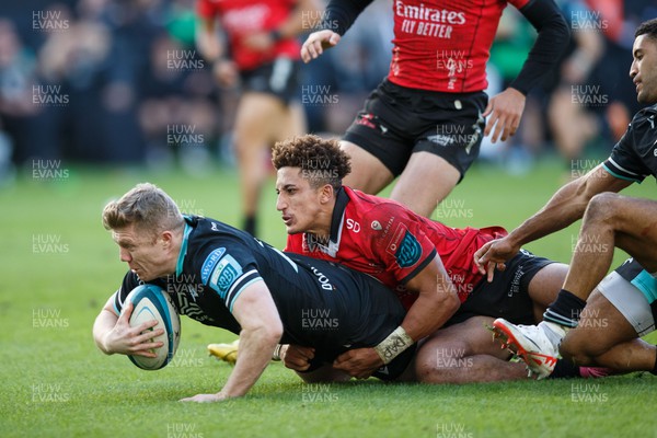 300324 - Ospreys v Emirates Lions - United Rugby Championship - Keiran Williams of Ospreys is tackled by Jordan Hendrikse of Lions but goes over for a try