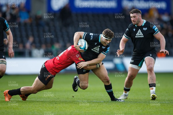 300324 - Ospreys v Emirates Lions - United Rugby Championship - Lewis Lloyd of Ospreys is tackled by JC Pretorius of Lions