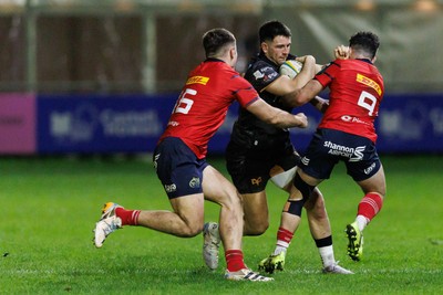 201225 - Ospreys v Munster - United Rugby Championship - Owen Watkin of Ospreys is tackled by Mike Haley and Paddy Patterson of Munster