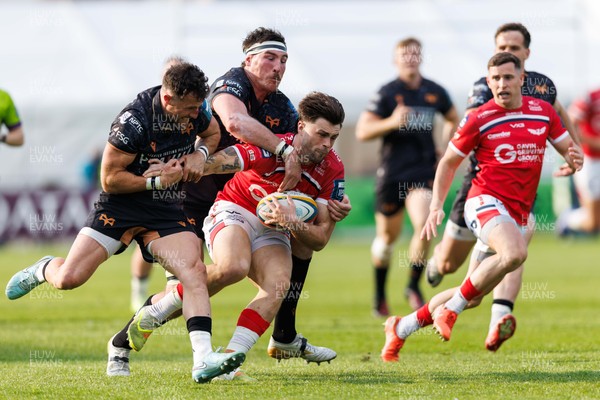 090526 - Ospreys v Scarlets - United Rugby Championship - Joe Roberts of Scarlets is tackled by Luke Morgan and Ryan Smith of Ospreys