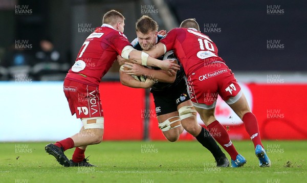 221218 - Ospreys v Scarlets - Guinness PRO14 - Olly Cracknell of Ospreys is tackled by James Davies and Hadleigh Parkes of Scarlets