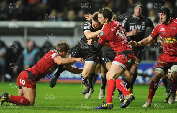 261212 - Ospreys v Scarlets - RaboDirect PRO12 -Dan Biggar of Ospreys is tackled by Aled Thomas and George North of Scarlets