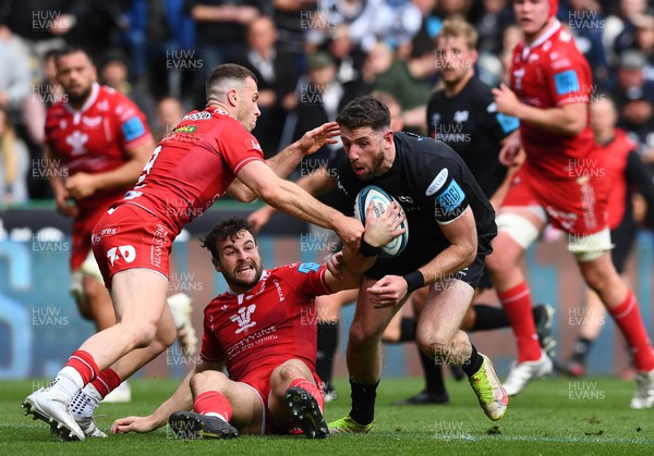 300422 - Ospreys v Scarlets - United Rugby Championship - Alex Cuthbert of Ospreys is tackled by Gareth Davies and Ryan Conbeer of Scarlets