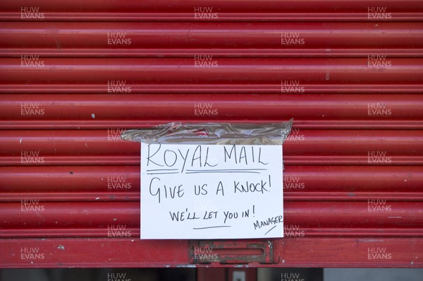 280320 - Picture shows Pontypridd Town Centre during the Covid-19 lockdown - A sign on a shop door for the postman