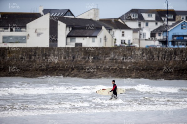 220620 - Picture shows a surfer entering the sea on the coast at Porthcawl on Monday morning, with temperatures set to sore later this week