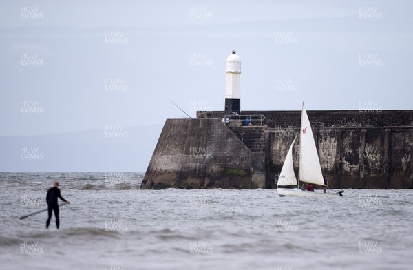 220620 - Picture shows paddle boarders and a sailing boat on the coast at Porthcawl on Monday morning, with temperatures set to sore later this week